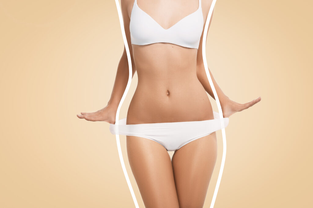 A woman in a white bikini confidently displays her toned stomach after undergoing VASER liposuction.